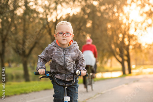 Мальчик в красных очках едет на велосипеде по дороге. Вечером, закат