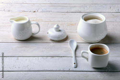 Cup of hot coffee espresso  coffee beans  jug of milk  and bowl with sugar on white background for copy space. Coffee concept.