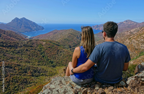 CLOSE UP: Unrecognizable couple sitting on rocky ledge overlooking the seaside.