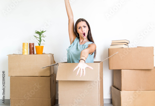 Portrait of a happy beatiful girl moving in the new house and unboxing cardboard  photo