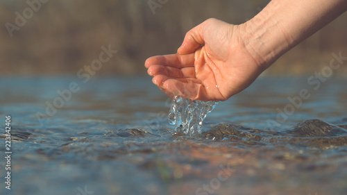 MACRO, DOF: Glistening river water flows out of unrecognizable girl's palm. © helivideo