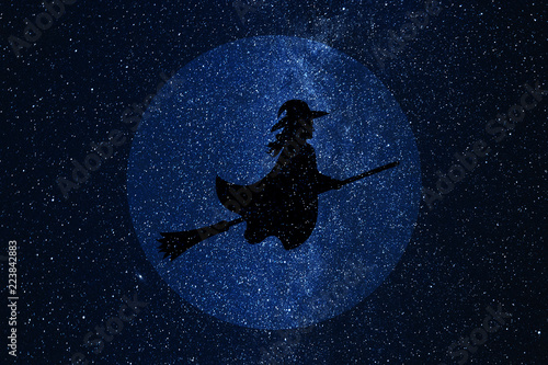 Fotografija Silhouette of witch flying on broomstick against background of night sky and full moon