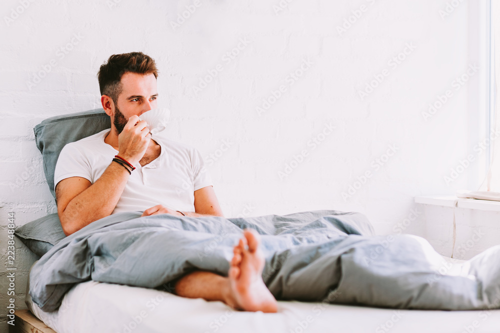 Young man drinking coffee in bed Young man drinking coffee in bed