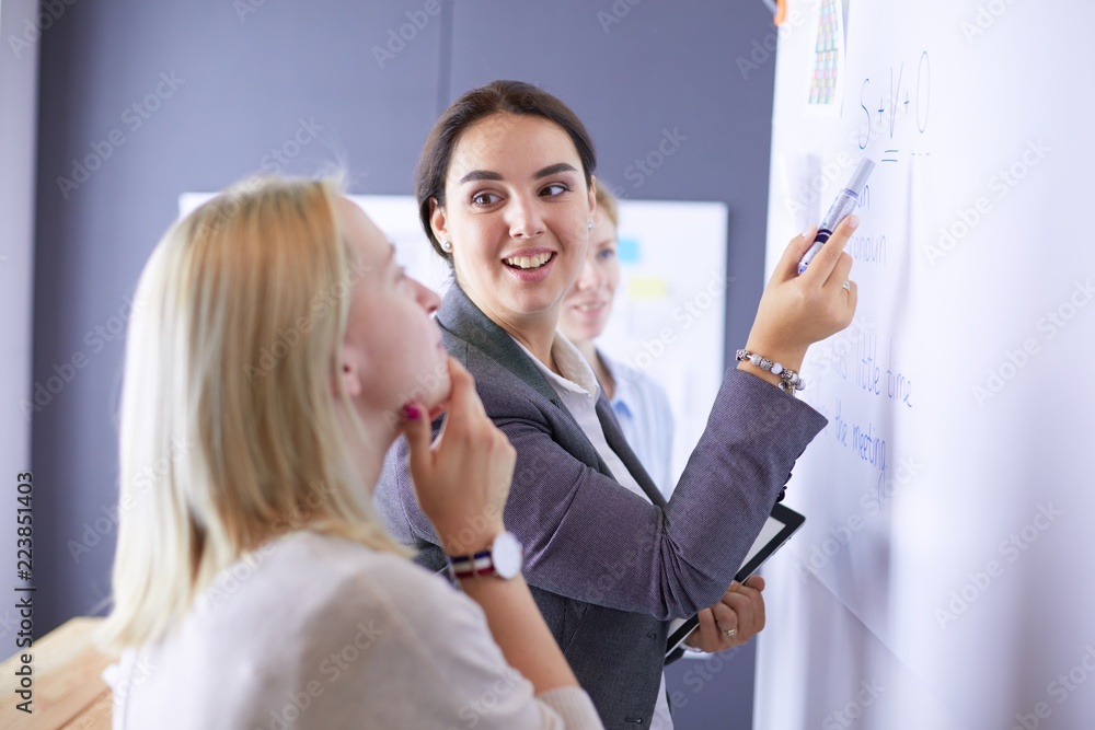 Business, education and office concept - business team with flip board in office discussing something. Business, education and office concept - business team with flip board in office discussing something.