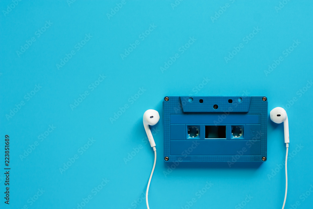 Retro cassette tape with earphones on blue background for music and relaxation concept Retro cassette tape with earphones on blue background for music and relaxation concept