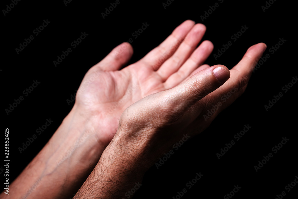 Male hands praying with palms up arms outstretched. Black background. Close up of man hand. Concept for prayer, faith, religion, religious, worship Male hands praying with palms up arms outstretched. Black background. Close up of man hand. Concept for prayer, faith, religion, religious, worship