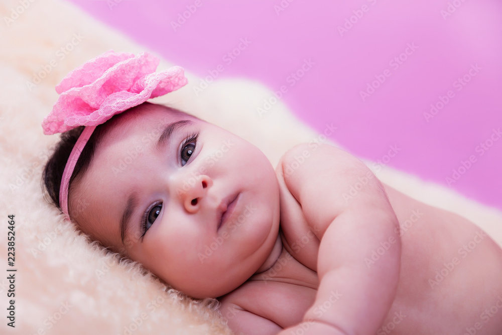 Cute, pretty, happy, chubby baby girl portrait, without clothes, naked or nude, on a fluffy blanket. Pink flower headband. Looking at camera. Four months Cute, pretty, happy, chubby baby girl portrait, without clothes, naked or nude, on a fluffy blanket. Pink flower headband. Looking at camera. Four months