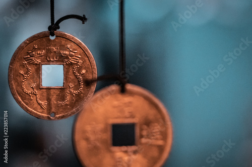 Oriental, magical pendants. Traditional asiatic and chinese currency, transformed into fortune coins with powerful engravings. Bronze, copper, gold necklace, black thread, blurry background.   photo