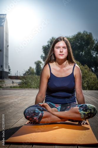 Young Caucasian woman in bodysuit relaxing by practicing yoga, gyan mudra and lotus position