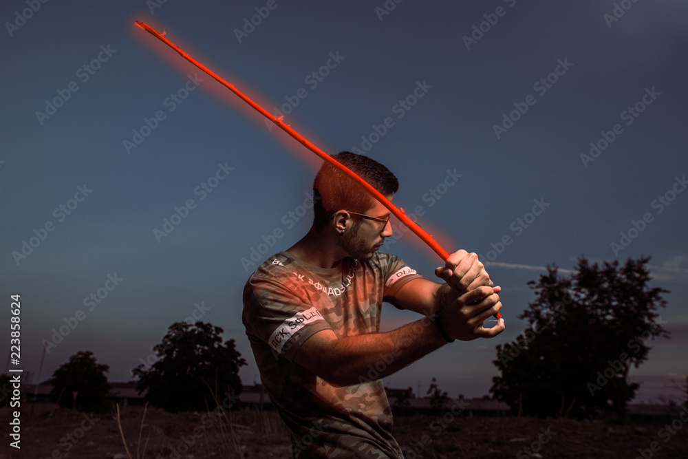 Fototapeta premium portrait of young man with glasses and beard playing with a stick