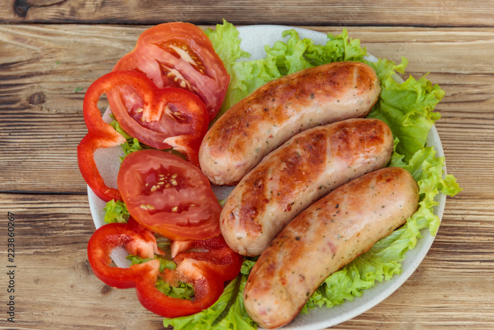 Grilled sausages with fresh vegetables on wooden table Grilled sausages with fresh vegetables on wooden table