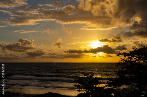 The sun hidden among dense clouds filters its rays on the sea.