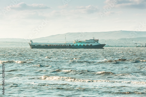 Sea cargo ferry. Mountanious background.