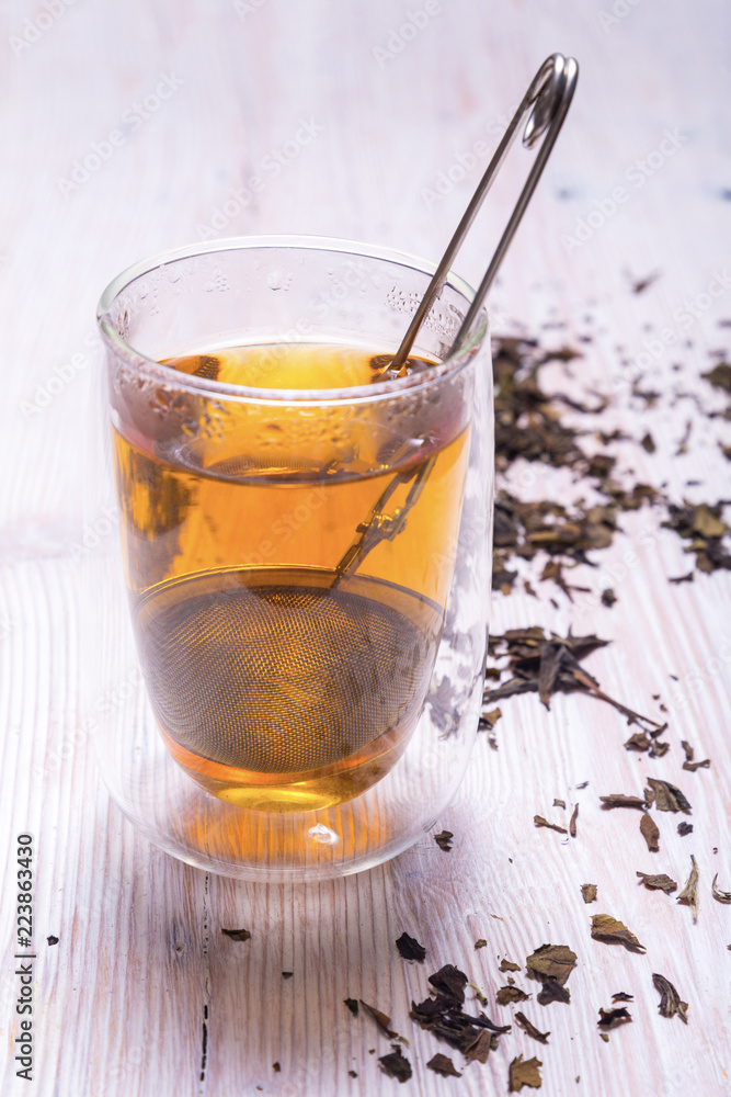 Double walled glass with tea and stainless steel tea infuser Double walled glass with tea and stainless steel tea infuser