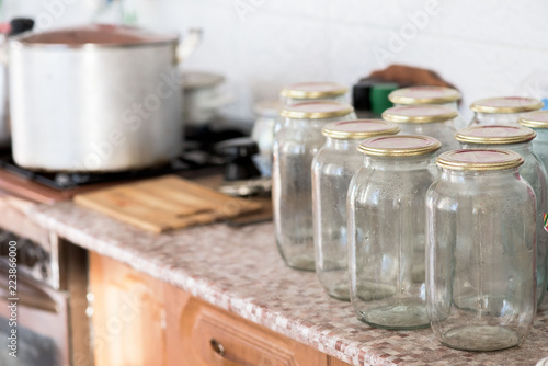 a lot of glass jars standing on the table in front of preserving . near gas stove