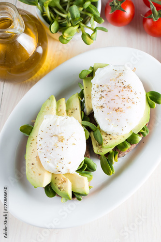 Avocado toast, cherry tomato on wooden background. Breakfast with toast avocado, vegetarian food, healthy diet concept. Healthy sandwich with avocado and poached eggs.