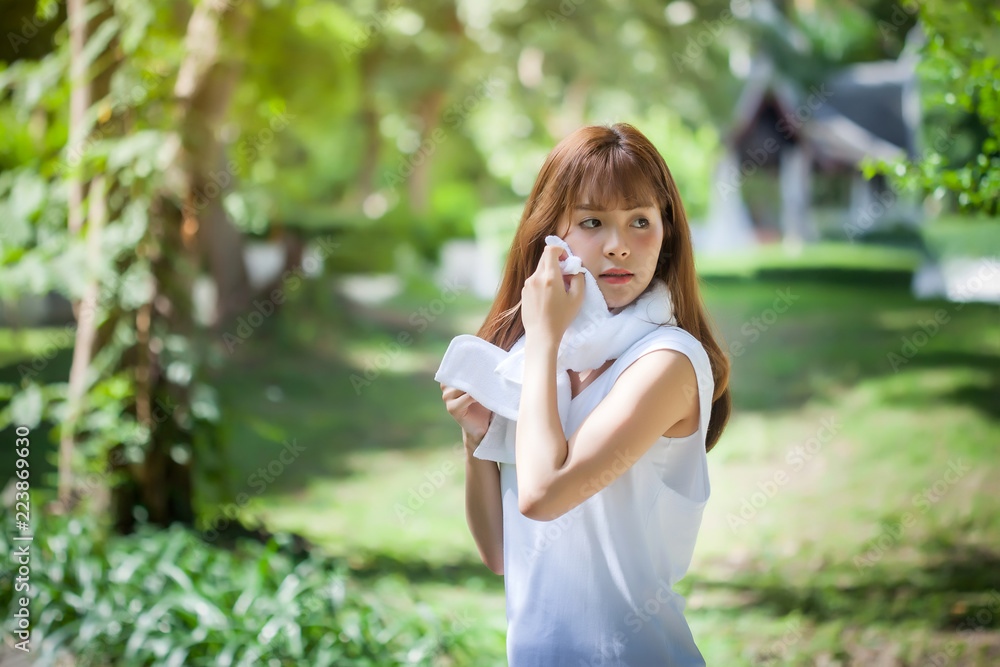 Young tired woman wiping her sweat with towel and refreshing after the completion of the exercise. Young tired woman wiping her sweat with towel and refreshing after the completion of the exercise.