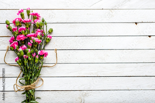 Pink cloves, spring flowers bouquet, overhead on white wooden background with copy space