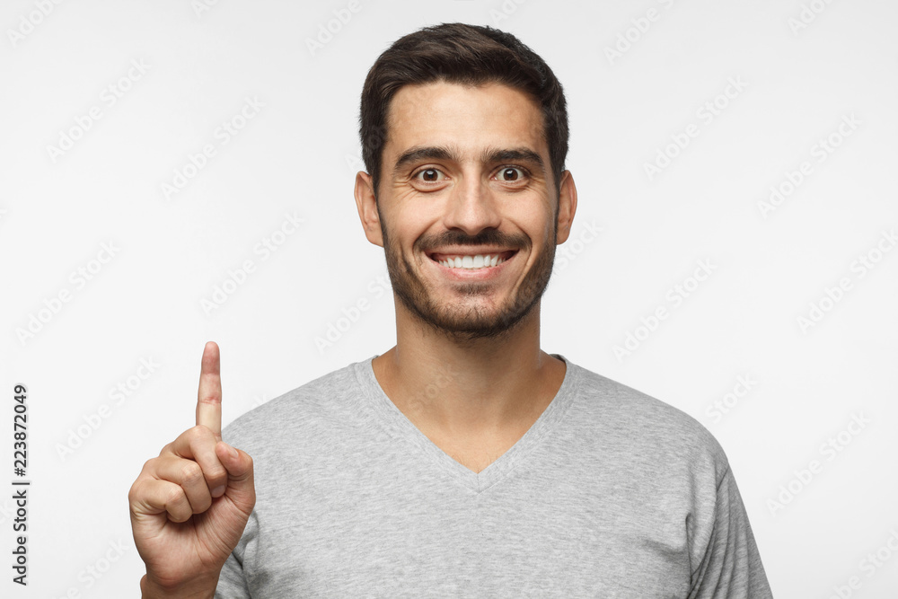 Attractive young man pointing up with his finger isolated on gray background Attractive young man pointing up with his finger isolated on gray background