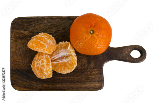 Mandarin - whole fruit and cantles on wooden board. Top view. Isolated on white.