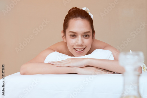 Close up of attractive young Asian woman smiling and getting Spa treatment on white bed with warm light flare