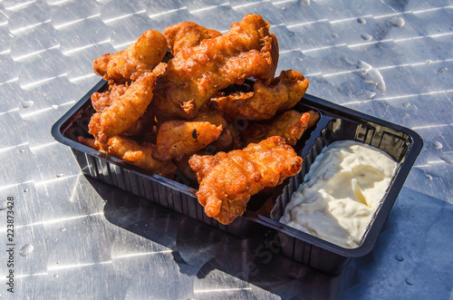 Black plastic box with traditional Dutch fish snack kibbeling (battered  chunks of fish) with sauce on a shiny metallic table top Stock Photo |  Adobe Stock