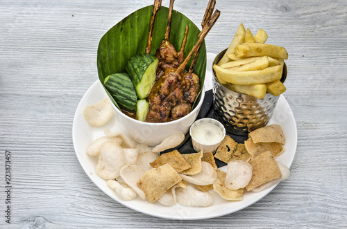 Indonesian inspired dutch dinner with chicken sateh, french fries, prawn crackers and mayonaise on a white wooden table photo