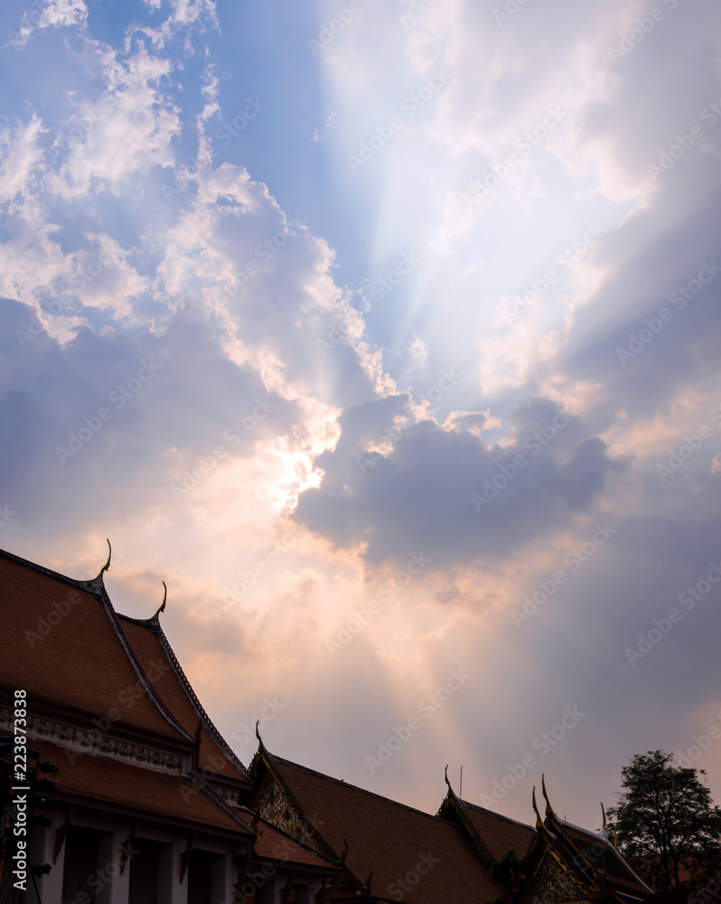 Sun beam behind the sunset clouds over the buddhist temple Sun beam behind the sunset clouds over the buddhist temple