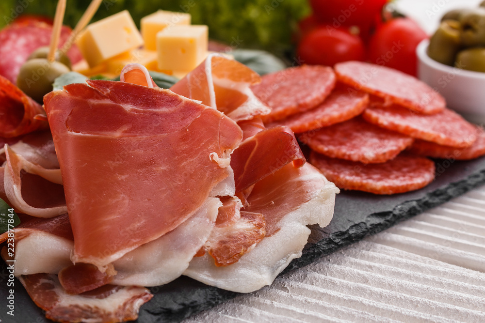 Cold smoked meat plate on a rustic wooden background