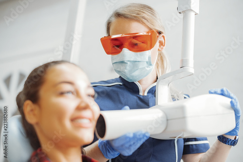 Close up of client smiling while dentist in blue uniform holding x-ray.