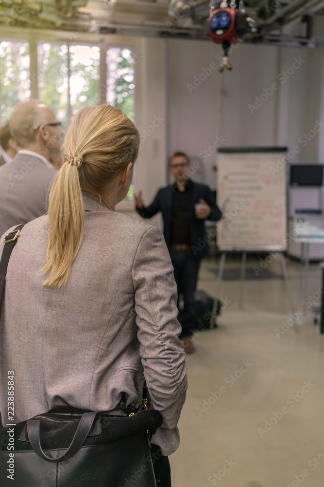 Managerin folgt aufmerksam einer Präsentation in einer Industriehalle Managerin folgt aufmerksam einer Präsentation in einer Industriehalle