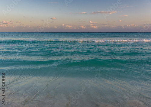 The tropical blue waters of the Caribbean Sea lap at the beach in Cancun, Mexico, as the day ends.