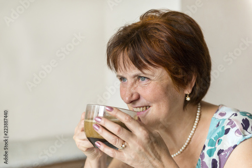 white adult woman drinks black coffee from mug and smiles
