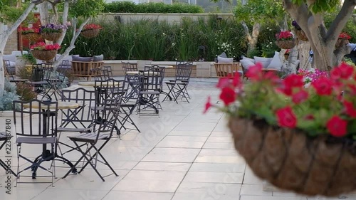 Conducting of the camera at the left on the right and refocusing from little tables in a garden on a suspended pot with flowers photo