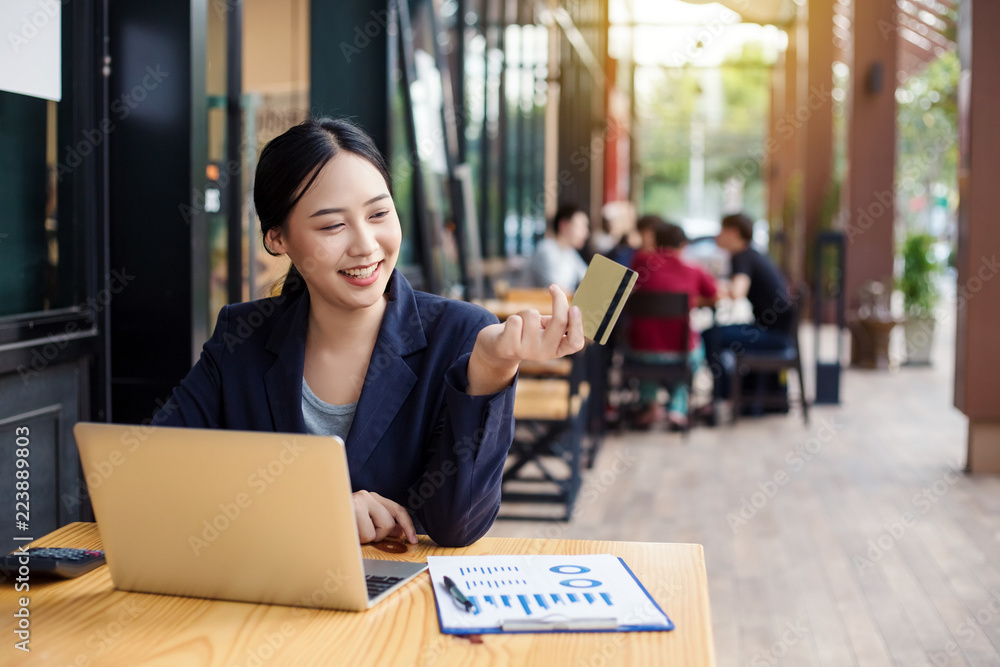 Young woman smiling. Business woman holds credit card and using laptop. Online shopping concept Young woman smiling. Business woman holds credit card and using laptop. Online shopping concept