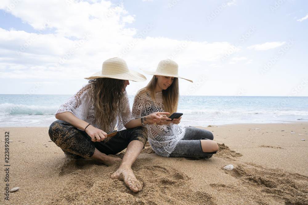 Girls using mobile phone in beach