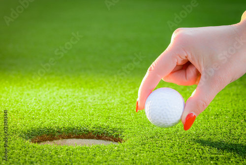 golfball regarded a woman's hand to the hole