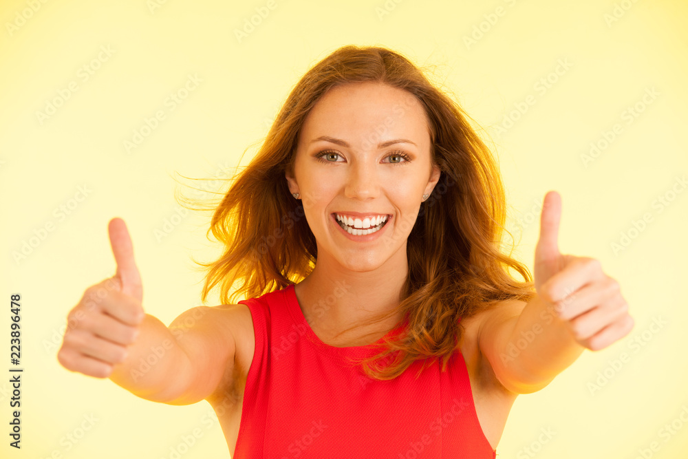 Beautiful young woman in red dress shows thumbs up as gesture for success Beautiful young woman in red dress shows thumbs up as gesture for success