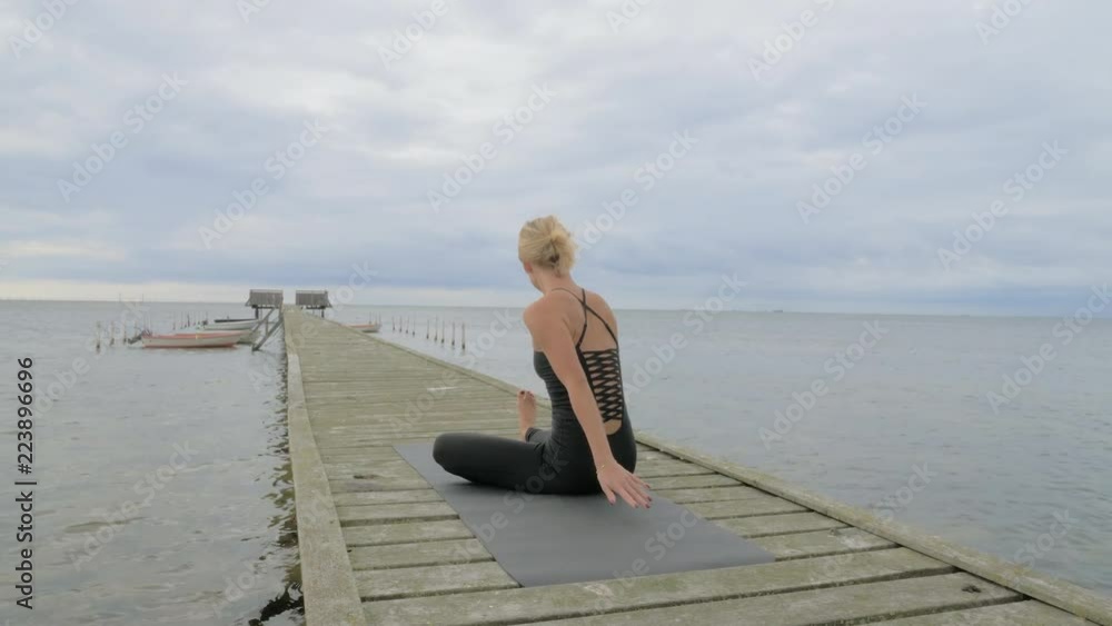 Beautiful young girl making yoga pose on the old wooden pier at the sea. Exercises calmness and harmony. Beautiful young girl making yoga pose on the old wooden pier at the sea. Exercises calmness and harmony.