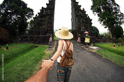 Woman in asian dress and hat holding man by hand travelling Asia photo