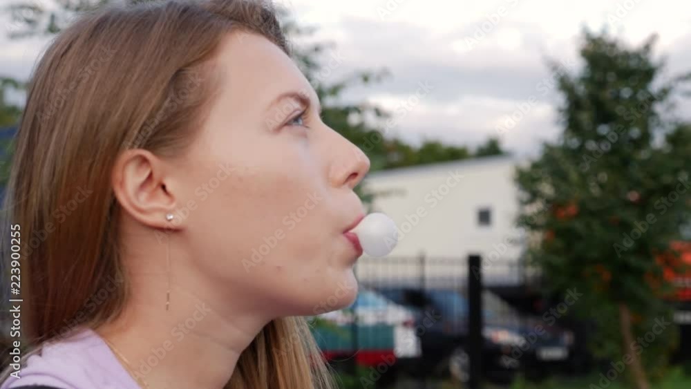 Beautiful teen girl chewing gum. Blond teenager blowing bubblegum candy. Cute female at sunset. Beautiful teen girl chewing gum. Blond teenager blowing bubblegum candy. Cute female at sunset.