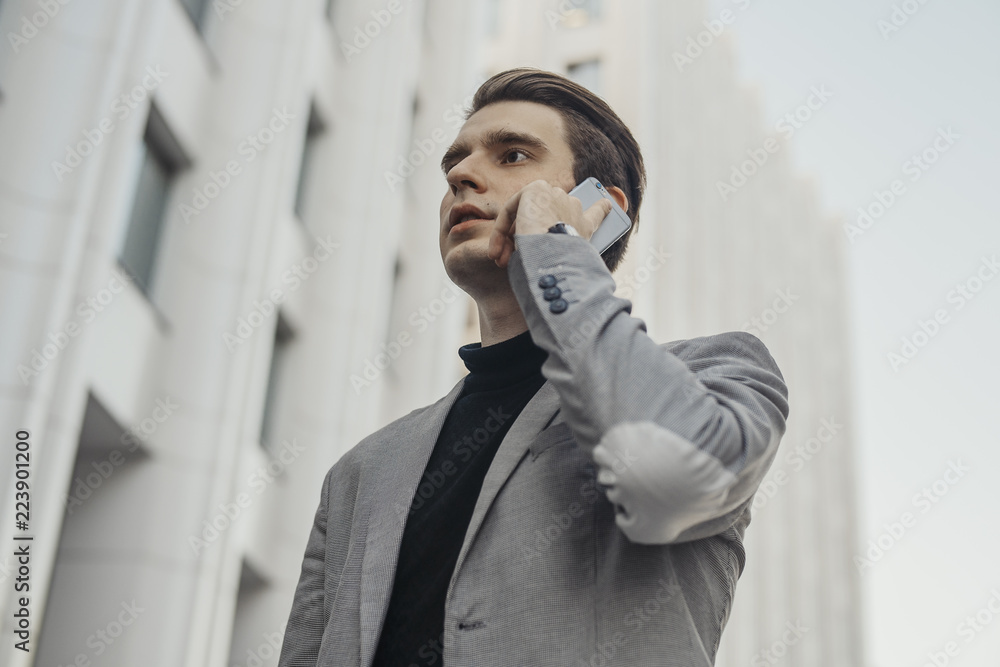 Close up of young businessman talking by mobile phone next to business center. Close up of young businessman talking by mobile phone next to business center.