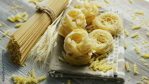 From above view of unprepared pasta of different kind placed on napkin on wooden background