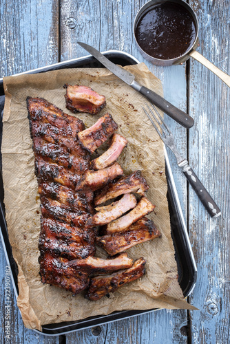 Barbecue spare ribs St Louis cut with hot honey chili marinade as top view in a rustic skilleton backing paper