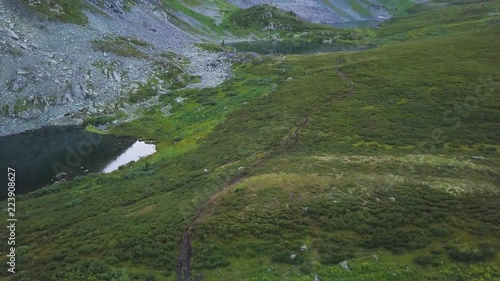 Aerial shot of a blue pond reflecting beautiful mountains in the background. Clip. Aerial view looking down at mountain lakes and streams, green grass and miountains background photo