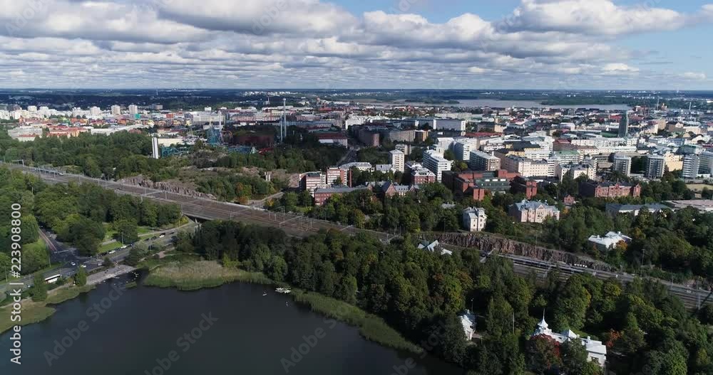 Aerial view of trains traveling through railroad during summer sunny day. Drone flying backwards. Amusement park with ferris wheel at background. Helsinki . Finland Aerial view of trains traveling through railroad during summer sunny day. Drone flying backwards. Amusement park with ferris wheel at background. Helsinki . Finland
