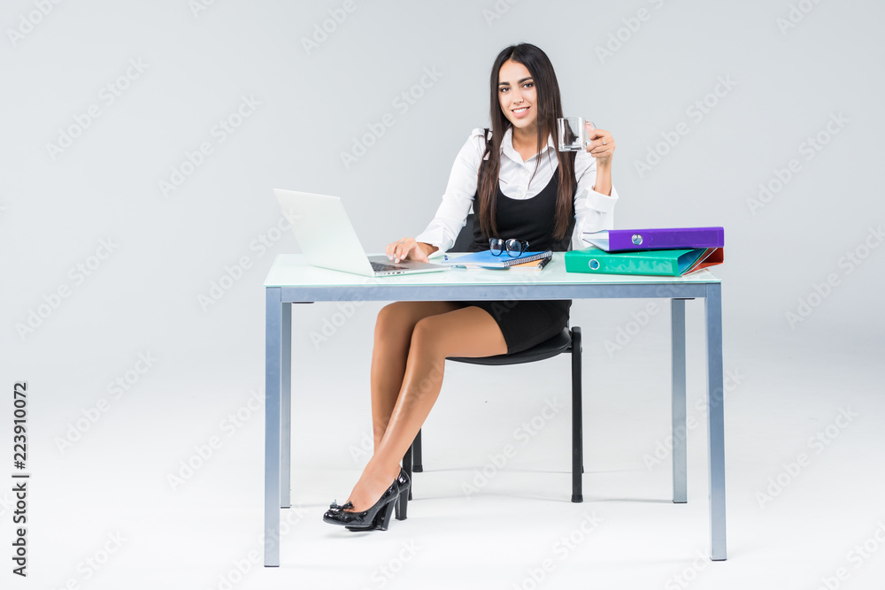 Beautiful business woman smile sitting at the desk working using laptop looking at screen typing on laptop isolated over white background Beautiful business woman smile sitting at the desk working using laptop looking at screen typing on laptop isolated over white background