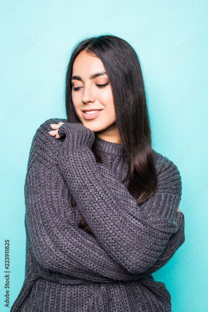 Young woman with a thoughtful friendly smile looking at the camera with her head tilted to the side and copy space isolated on blue background Young woman with a thoughtful friendly smile looking at the camera with her head tilted to the side and copy space isolated on blue background