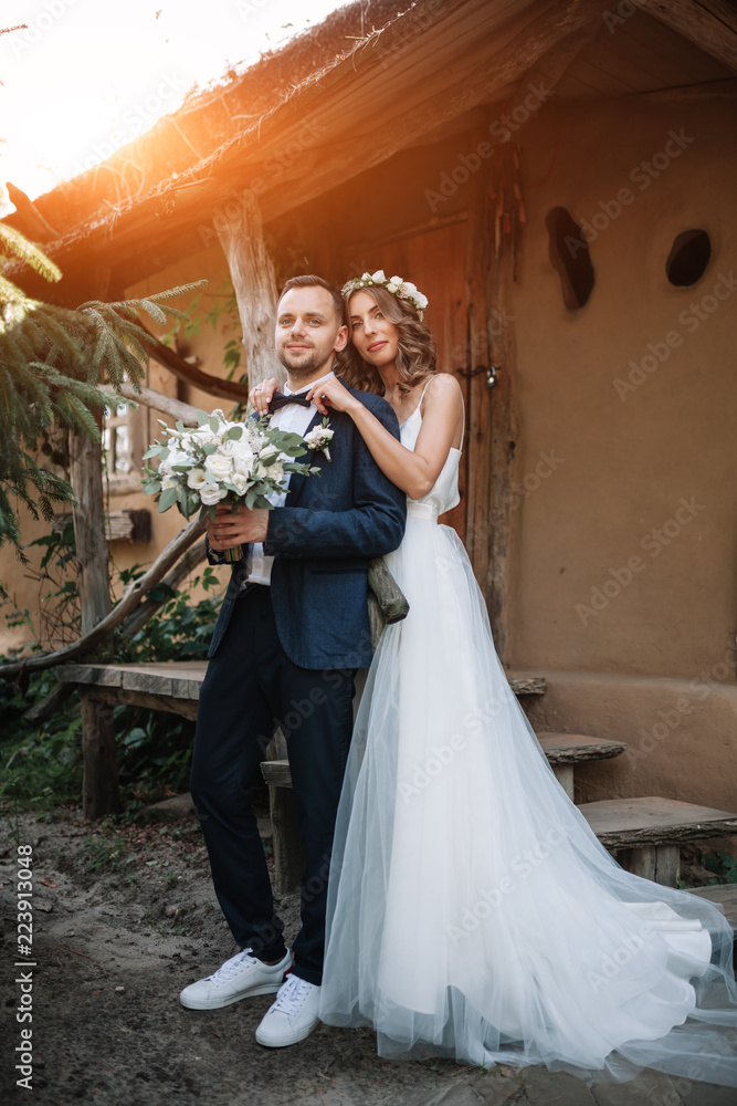Fototapeta premium Bride and groom at wedding Day walking Outdoors on summer nature. Bridal couple, Happy Newlywed woman and man embracing in green park. Loving wedding couple outdoor. Bride and groom