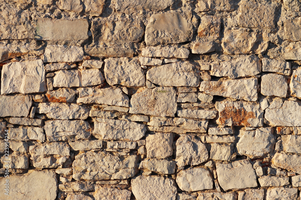 Ancient medieval stone masonry. Texture of a fragment of a wall of an old structure. A background for design and creative work. Decoration and exterior decoration of the building. Construction works. Ancient medieval stone masonry. Texture of a fragment of a wall of an old structure. A background for design and creative work. Decoration and exterior decoration of the building. Construction works.